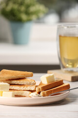 Tasty toasts with butter served on white wooden table
