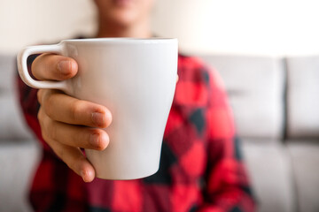 person showing white  cup of coffee at home