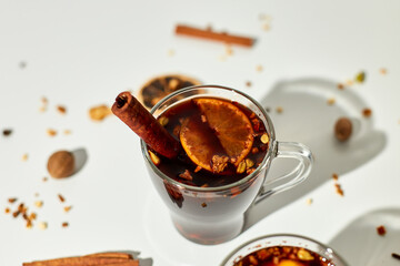 Cup with Christmas mulled red wine with spices and oranges on a white background hard light, traditional hot drink at Christmas, festive cocktail