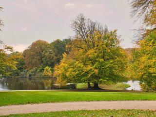 Frederiksborg Castle Park in autumn with mighty deciduous trees on the garden meadows