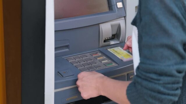 Woman entering pin code at ATM