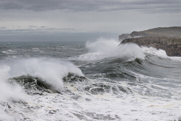 Huge waves crashing on the cliffs. Weather alert on the coast with strong wind and large waves. 