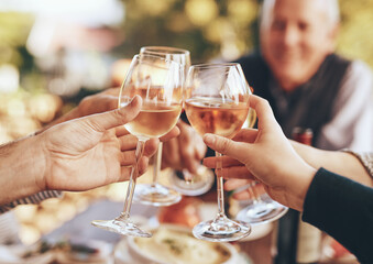 Hands, glass and cheers with a group of people drinking alcohol together outdoor in celebration of...