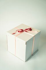 white cardboard gift box tied with a red ribbon on a white background