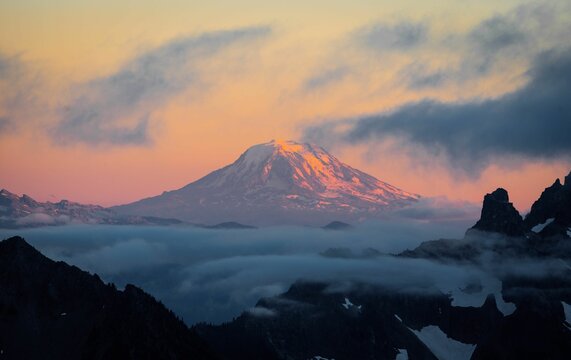 Beautiful scenery of the snowy peak of the Mount Adams during sunset with clouds in the foreground