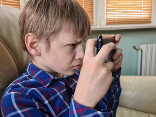Closeup of boy using smartphone, looking at screen, curious child is holding phone in hands