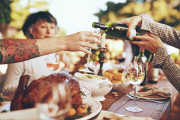 Dinner, party and celebrate with hands and wine, wine glass to pour for drink, people with food outdoor, holiday or anniversary celebration. Festive, event and table with feast, friends and family.