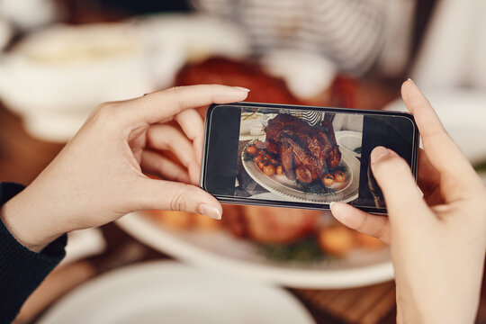 Phone, photograph and thanksgiving with the hands of a woman taking a picture of food on a dinner table. Mobile, social media and Christmas with a female using her smartphone to photo a roast meal