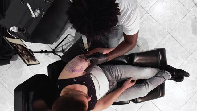 Tattoo master makes a tattoo on a man body. View from above. High quality 4k footage .