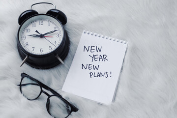 Happy New Year concept. The notebook with new year new plans text on white fur background.