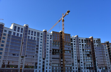 Fototapeta na wymiar Construction of a residential multi-storey building with apartments and flat. Cranes on pouring concrete in formwork. Tower crane on construction in built environment. Buildings renovation.