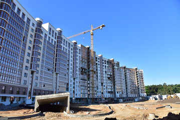 Construction of a residential high-rise building with apartments and parking. Cranes on pouring concrete in formwork. Tower crane on construction in built environment. Buildings renovation.