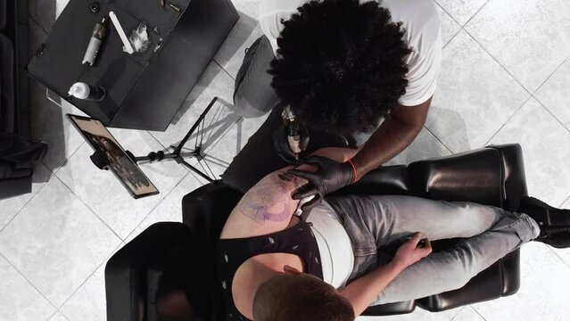 Tattoo master makes a tattoo on a man body. View from above. High quality 4k footage .
