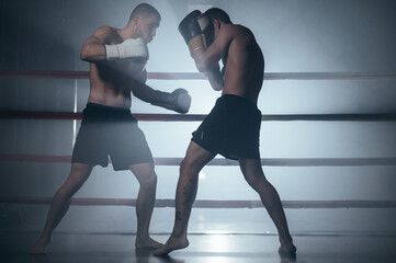 Two shirtless muscular man fighting Kick boxing combat in boxing ring. High quality photo