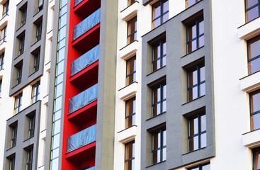 Fototapeta premium Facade of a new residential building with windows in flats. Construction of the skyscraper. Tall house renovation project. Painting facade of building during construction of housing under renovation