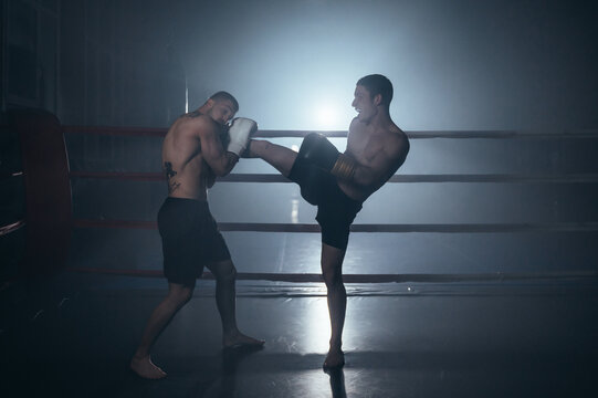 Two shirtless muscular man fighting Kick boxing combat in boxing ring. High quality photo