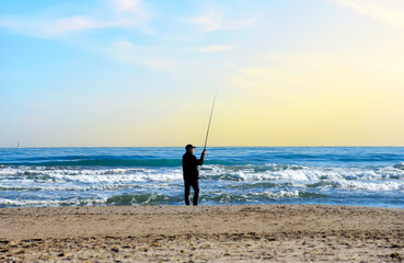 Fisherman catches fish on the coast near the sea. Catching fish in the sea from the shore. Fishing...