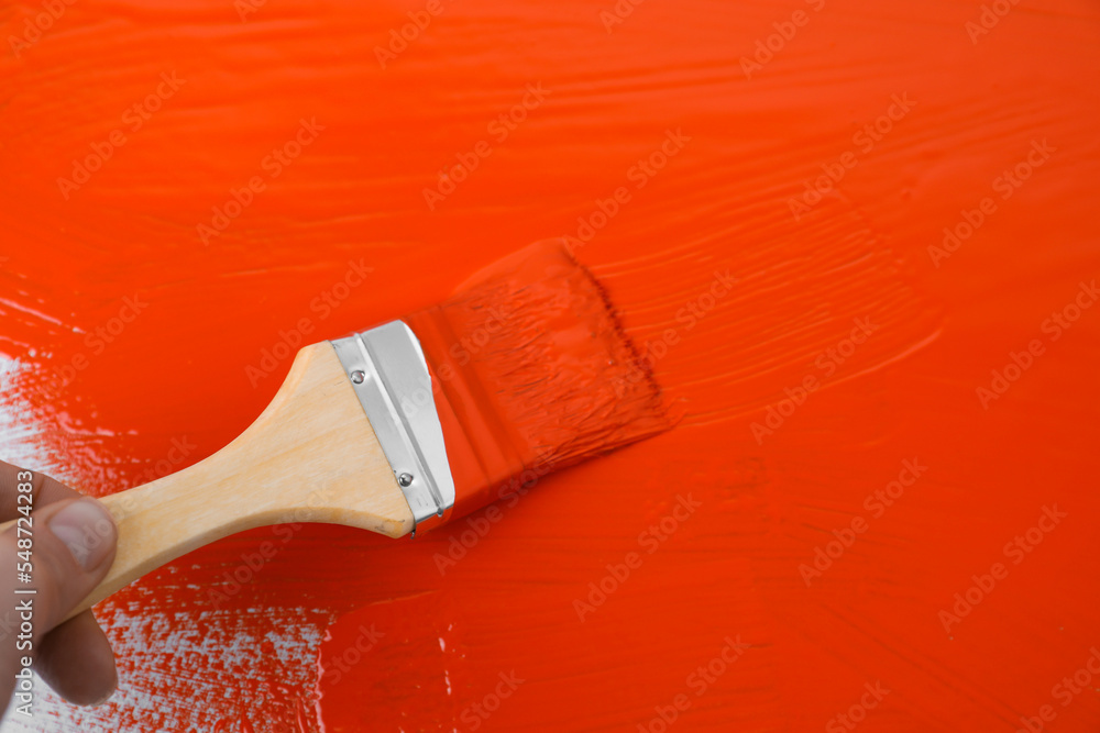 Poster Man applying orange paint with brush on white background, closeup