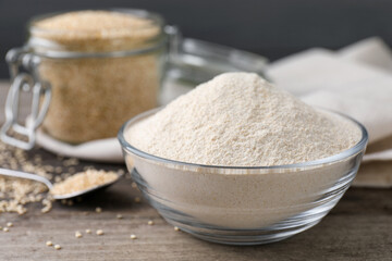 Glass bowl with quinoa flour and seeds on table, closeup