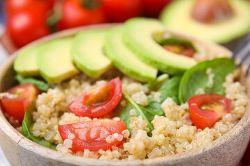 Delicious quinoa salad with tomatoes, avocado slices and spinach leaves, closeup