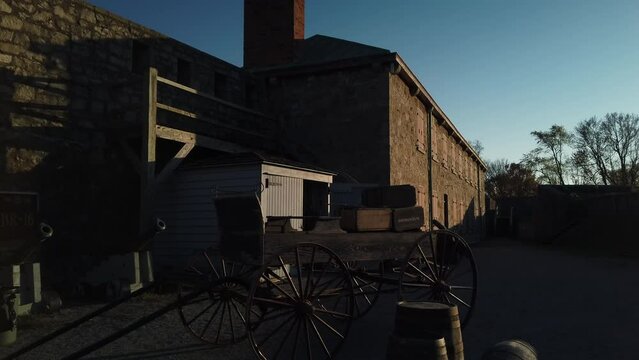 Exterior tilt down from late afternoon sky to reveal Fort Erie museum courtyard with barracks, cannons and empty horse buggy