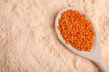 Spoon with lentil grains on flour, top view. Space for text