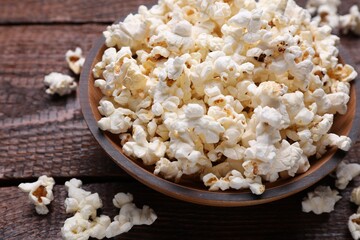 Bowl of tasty popcorn on wooden table, closeup