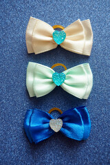 two blue and a white bow for dogs with long hair lie on a blue shiny background. view from above....
