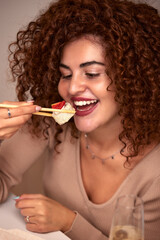 Young woman eating sushi asian food and noodles using choopsticks from take away delivery