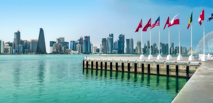 Panoramic city skyline view on the waterfront in Doha, Qatar. Some flags of nations qualified for the World Cup Qatar 2022 in the foreground..