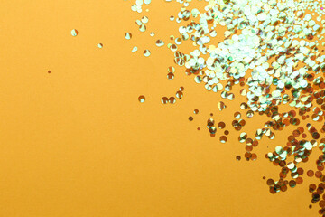Fototapeta na wymiar Shiny bright glitter on orange background. Space for text