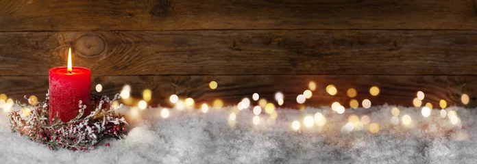 Fototapeten Weihnachtskerze in der Winterschneelandschaft mit magischen Lichtern. Weihnachtspanorama, Banner. Erster Adventssonntag. Hölzerner Hintergrund mit Kopienraum. © Floydine
