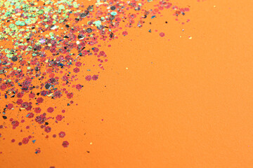 Shiny bright glitter on orange background. Space for text
