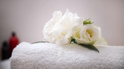 Fototapeta na wymiar Folded bath towel and beautiful flowers in bathroom, closeup
