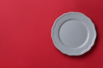 Clean grey plate on red background, top view. Space for text
