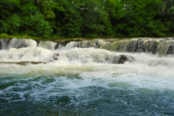 Blurred view of river with rapids near forest