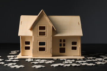 House model and puzzles on black table depicting destruction after earthquake