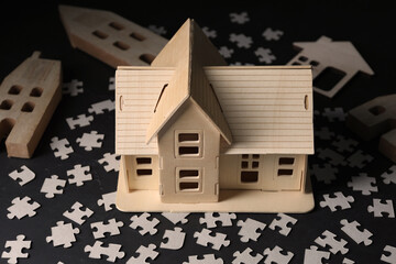 House model and puzzles on black table depicting destruction after earthquake