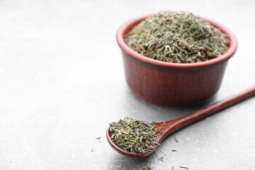 Fototapeta premium Bowl and spoon with dried thyme on grey table, closeup. Space for text