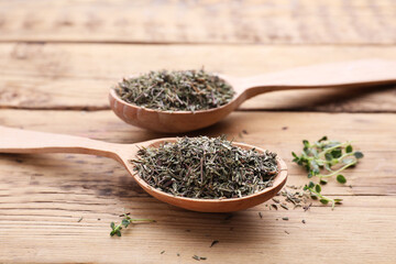 Spoons with dried and fresh thyme on wooden table, closeup