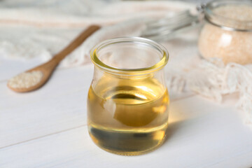 Jar of organic sesame oil on white wooden table, closeup