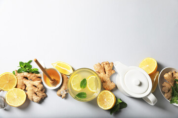 Delicious ginger tea and ingredients on light grey background, flat lay. Space for text