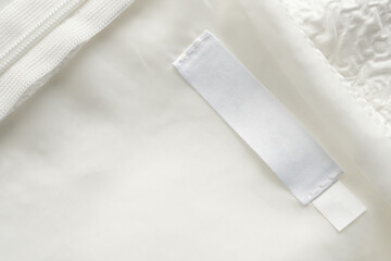 Blank white laundry care clothes label on fabric texture background