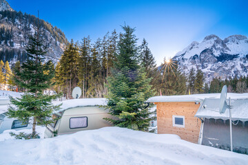 Camping im Winter im Schnee. Reisemobil und Wohnwagen im Winter zum Campen in den Bergen. Schnee und Eis in der Schweiz