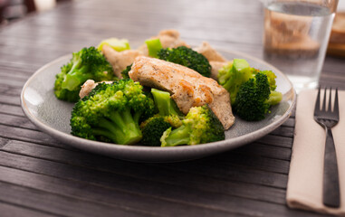 pieces of fried chicken breast with boiled broccoli on plate for breakfast