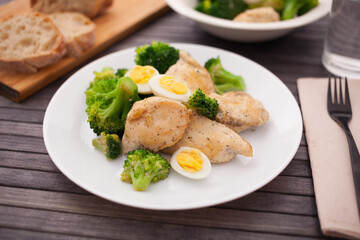 pieces of fried chicken breast with boiled broccoli and quail eggs on plate for lunch