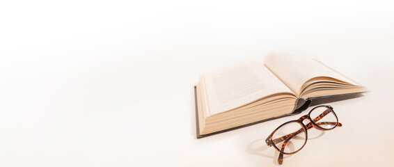 Long-sighted glasses and a big book. laying on a white background. Elderly eye health problems.