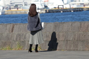 防波堤で一人で遠くを眺める若い女性