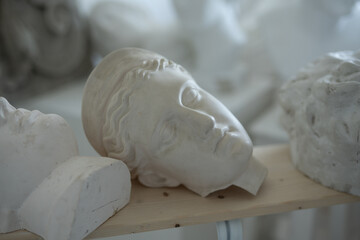 Photo of handmade marble heads of greek people in workshop of sculptor.