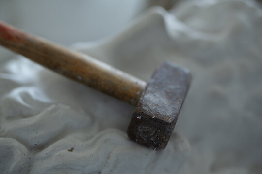 Closeup photo of hammer on marble bust of greek man.